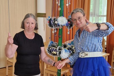 Bewohnerin und Mitarbeiterin mit einem Maibaum