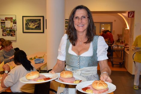 Mitarbeiterin serviert Leberkäsjause