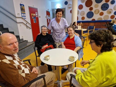 Gruppenfoto der Gäste bei Tisch mit Pflegemitarbeiterin