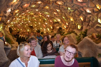 Eine Bahn, besetzt mit mehreren Menschen, fährt durch eine beleuchtete Grotte.