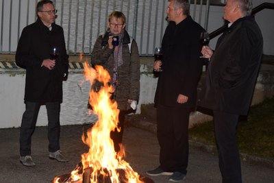 Vier Männer stehen im Freien um eine Schale in der Feuer brennt.