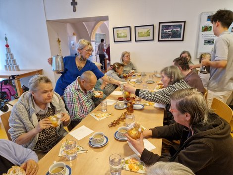 Mitarbeiterin und Zivildiener bewirten BewohnerInnen bei Tisch