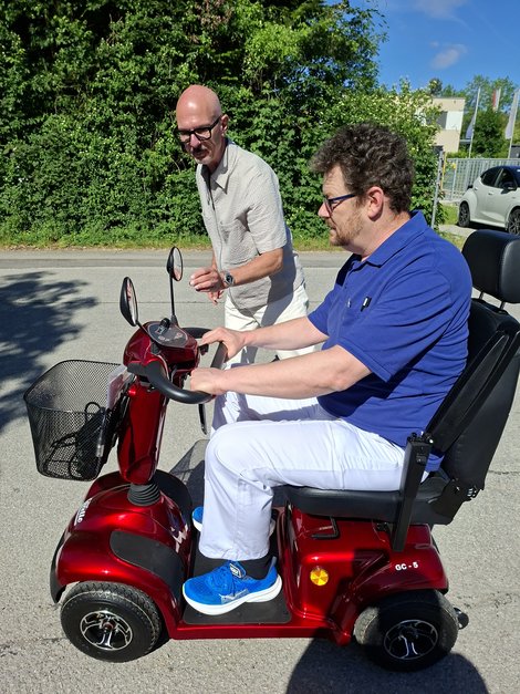 Mitarbeiter LPBZ Cumberland auf Seniorenfahrzeug mit Mitarbeiter Fa. Carello