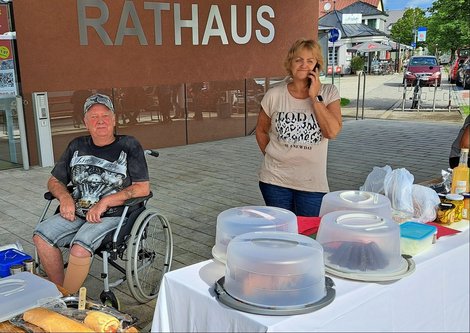 Tisch mit Kuchen, dahinter 2 Personen und im Hintergrund die Aufschrift "Rathaus"