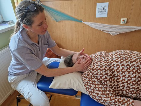 Physiotherapeutin massiert/streichelt Bewohnerin das Gesicht