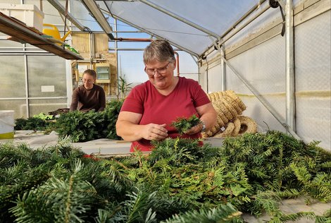 zwei Mitarbeiter bei Adventkranzherstellung