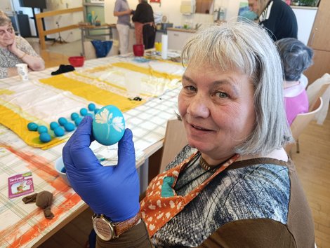 Bewohnerin färbt blaues Osterei mit Blattmuster