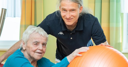 Physiotherapeut August Marschall und Bewohnerin mit Ball