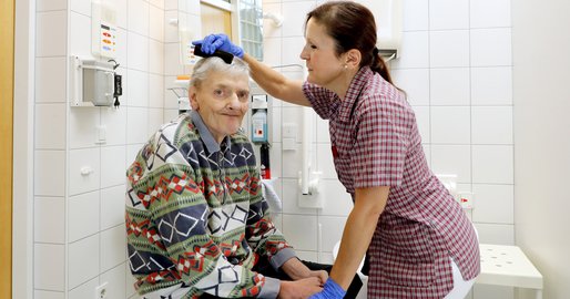 Mitarbeiterin kämmt einem Bewohner die Haare