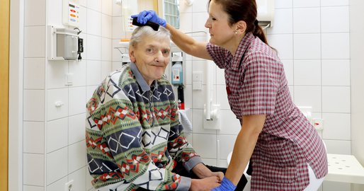 Mitarbeiterin kämmt einem Bewohner die Haare