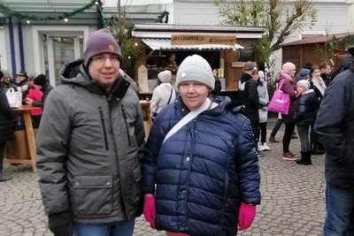 Ein Mann und eine Frau in Winterkleidung stehen inmitten von Christkindlmarkthütten.