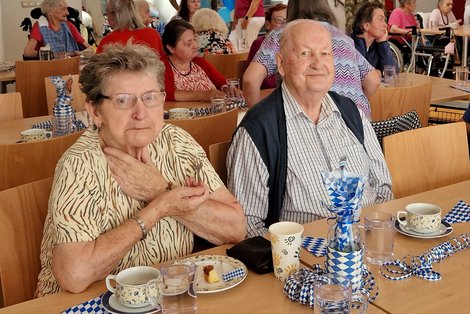 2 Gäste beim Kaffeetisch und blau-weißer Oktoberfestdeko