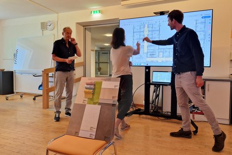 Mitarbeiterin mit Architekt und Baumeister beim Plan