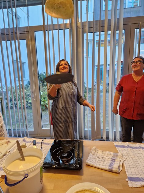 DGKP Verena König schupft Palatschinke sehr hoch, Köchin schaut zu