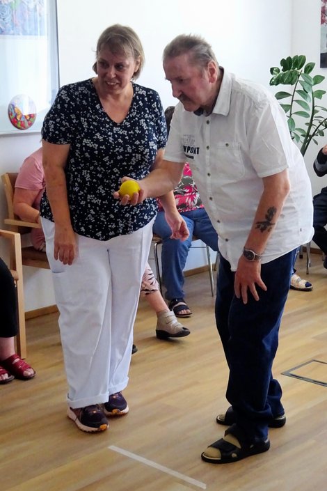 Bewohner mit Ball in Startposition, daneben eine Mitarbeiterin 