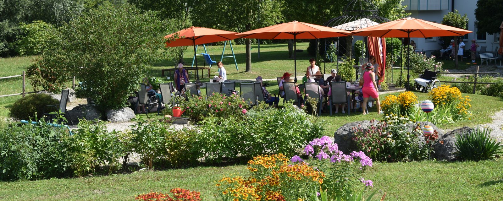 Garten mit Sonnenschirmen, Tischen und Sesseln