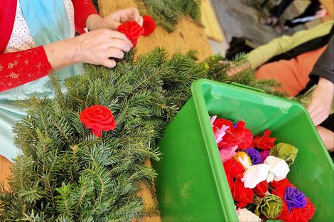 Bewohnerin dreht Krepppapierrosen für Kranz