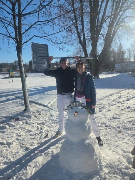 2 Zivildiener mit fertig gebautem Schneemann