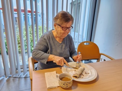Bewohnerin isst Palatschinke und trinkt Kaffee