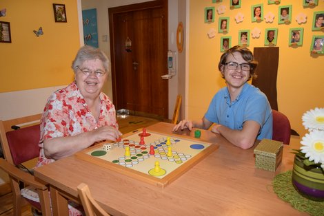 Praktikant spielt mit Bewohnerin Brettspiel