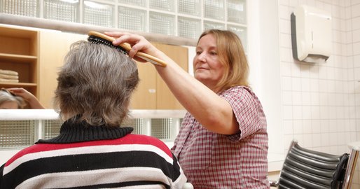 Mitarbeiterin kämmt einer Bewohnerin die Haare