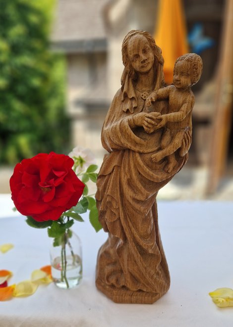 Marienstatue aus Holz und rote Rose in Vase