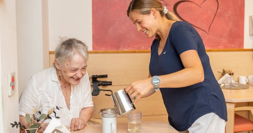 Mitarbeiterin schenkt Bewohnerin Tee ein