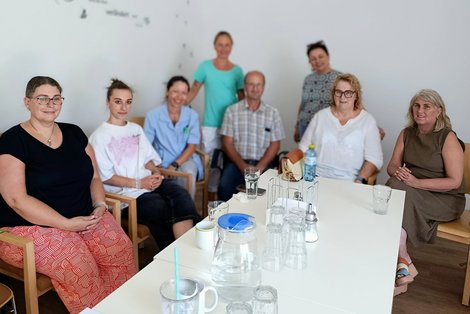 Gruppe von MitarbeiterInnen bei Tisch