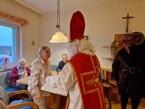 Bewohnerin steht vor Nikolaus und Krampus