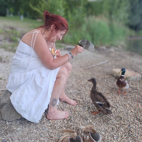 Bewohnerin im weißen Kleid am Pichlingerseestrand beim Enten füttern