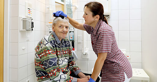 Mitarbeiterin kämmt einem Bewohner die Haare