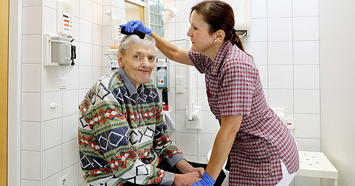 Mitarbeiterin kämmt einem Bewohner die Haare