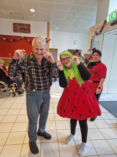 Mitarbeiterin im Erdbeer-Kostüm und Bewohner beim Tanz