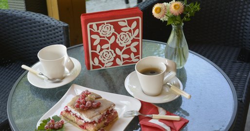 Kaffeetassen und Kuchen auf rundem Tisch