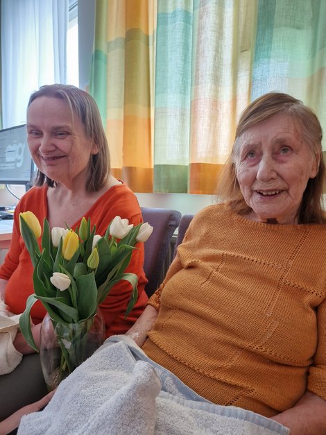 Bewohnerinnen mit Blumen und Lächeln im Gesicht