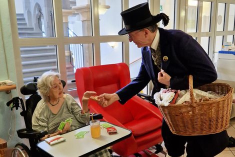 Bewohnerin im Rollstuhl erhält Lebkuchenherz von Mitglied des Gmundner Trachtenvereins