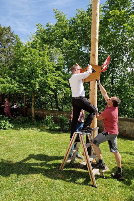 Dir. David See bringt Schild am Maibaum an.