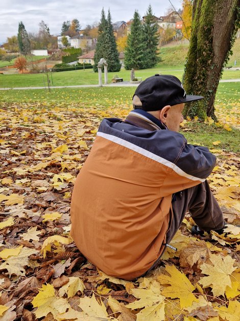 Mann sitzt im Laub