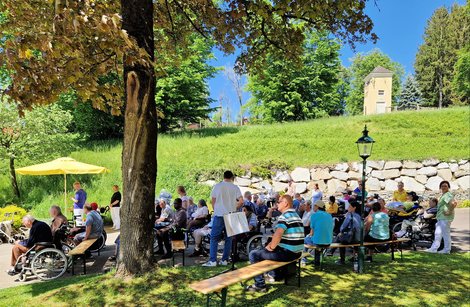 BewohnerInnen im Schatten unter Baum beim Maibaumfest