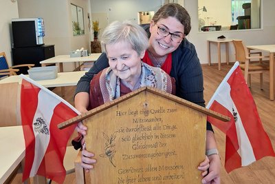 Bewohnerin und Mitarbeiterin mit Maibaumschild