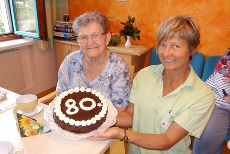 Mitarbeiterin hält Torte für Geburtstagskind Leopoldine Gruber