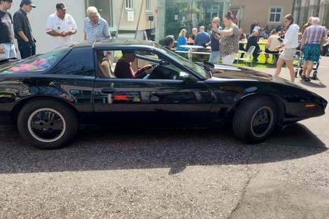 Bewohner sitzt im Auto, andere beobachten KITT von außen