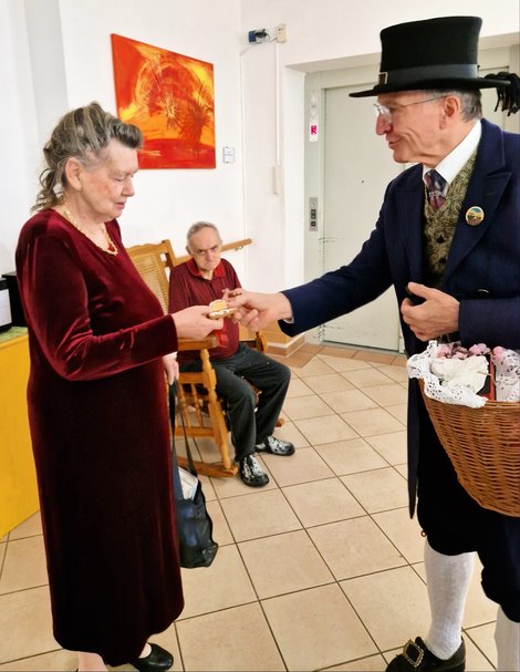 Bewohnerin erhält Lebkuchenherz vom Mitglied des Gmundner Trachtenvereins