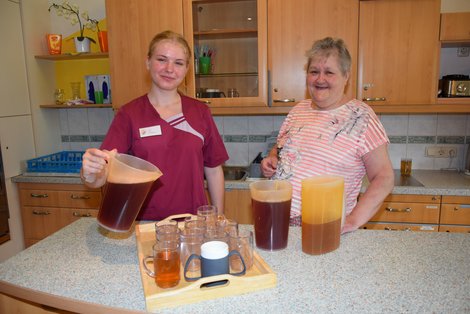 Praktikantin mit Bewohnerin in Küche beim Saft-Einschenken