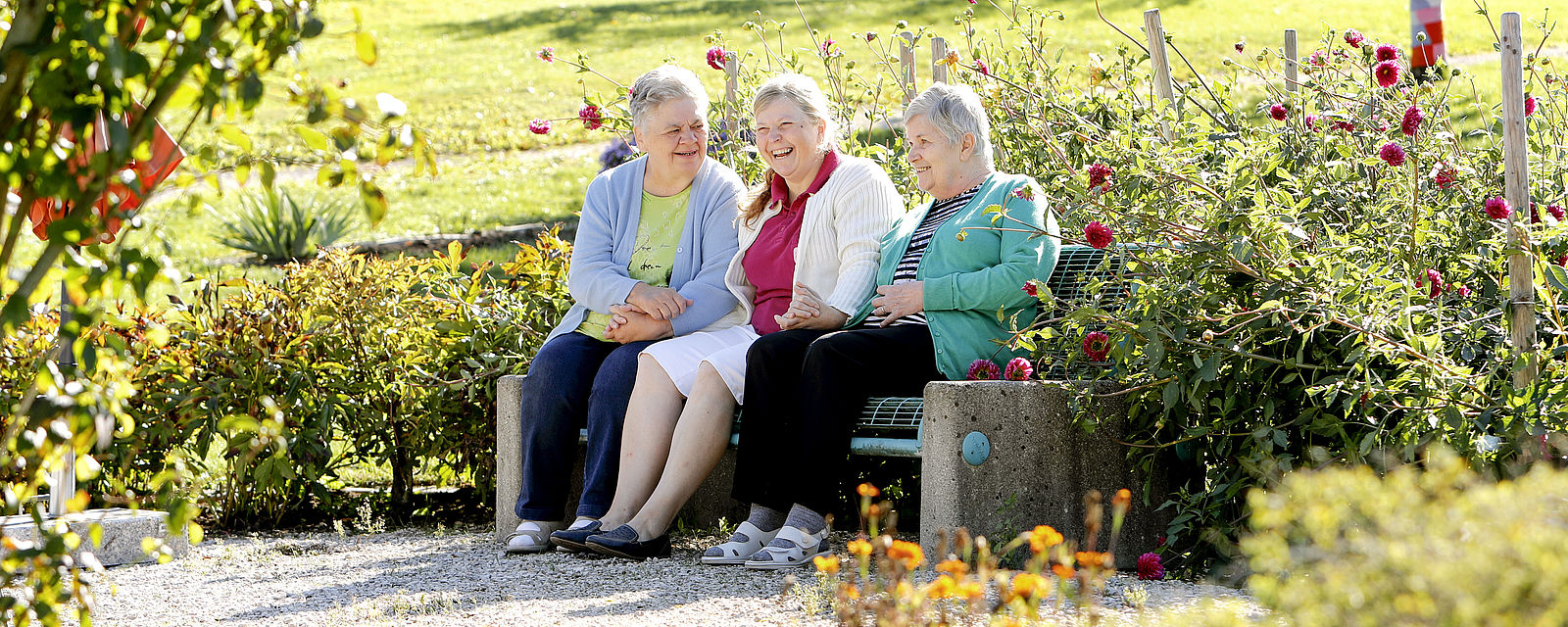 3 Bewohnerinnen sitzen auf einer Sitzbank im Garten