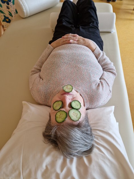 Frau auf Liege mit Gurkenscheiben am Gesicht