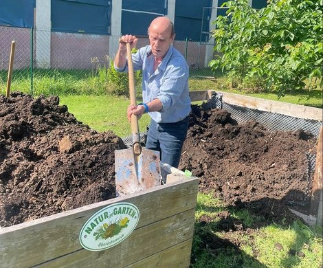 Bewohner füllt Erde in Hochbeet