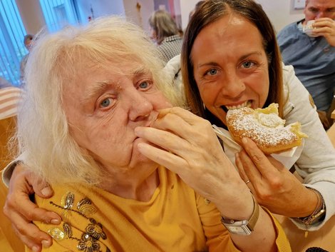 Bewohnerin und Mitarbeiterin beißen in den Bauernkrapfen