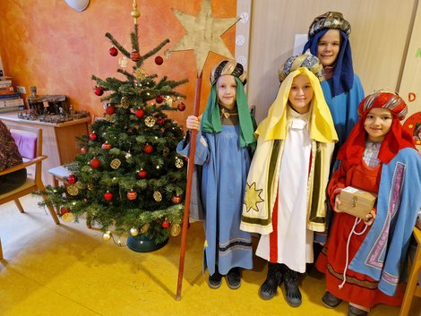 Sternsinger neben Christbaum im Wohnzimmer