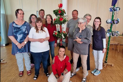 Gruppenfoto rund um zwei Maibäume